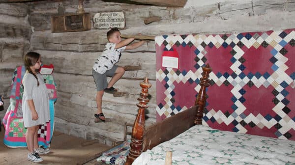 A little boy climbs the peg steps inside a cabin at Lincoln Pioneer Village & Museum
