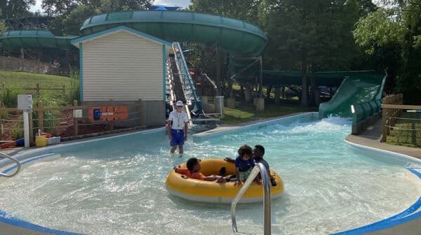 Father and two sons sit in innertube at end of Watubee waters slide at Holiday World during destination video shoot