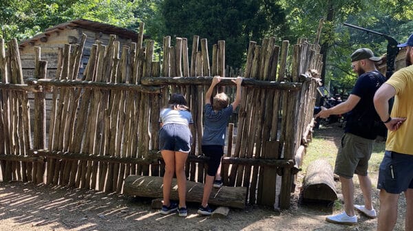 Two children look through the chicken cook fence at the Living Historical Farm inside Lincoln Boyhood National Memorial as a crew films them for a destination video